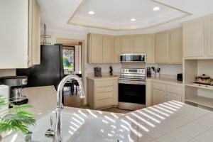 a kitchen with white cabinets and a black refrigerator at Spacious Villa with Spectacular Golf Course Views in La Quinta