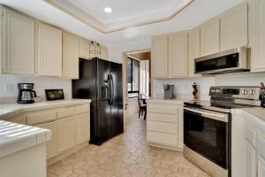 a kitchen with white cabinets and a black refrigerator at Spacious Villa with Spectacular Golf Course Views in La Quinta +45 photos