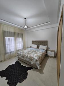 a bedroom with a large bed and a rug at Moga Appartment in Essaouira