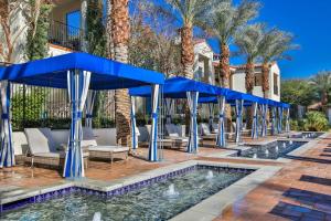 un complejo con una piscina con sombrillas azules en Gorgeous Ground Floor Villa Near Main Pool, en La Quinta