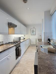 a large kitchen with white cabinets and a sink at Sea Blue House, Cullercoats in Cullercoats