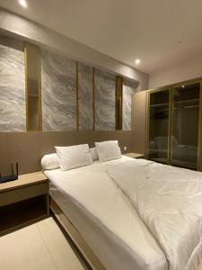 a large white bed in a room with windows at Luxury 2BR Benson Apartment, Pakuwon Mall in Surabaya +6 photos