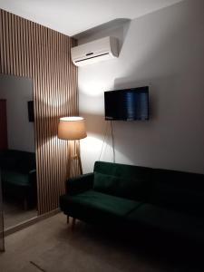 a living room with a green couch and a television at BAARIA PORTO rooms in Milazzo