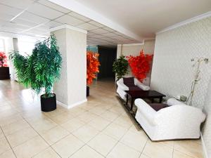 a lobby with white furniture and plants and red flowers at Luisa Lux Apartment - Sat Vacanta in Mamaia