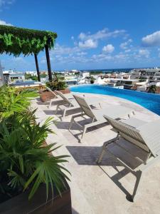a group of lounge chairs next to a swimming pool at Condo en el corazon de Playa del Carmen in Playa del Carmen