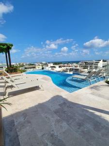 a swimming pool with chairs and a view of the ocean at Condo en el corazon de Playa del Carmen in Playa del Carmen