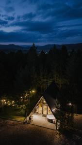 a small cabin in the woods at night at Pinery Blidinje A-Frame House in Blidinje