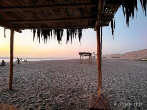 a beach with a hut and people on the beach at CASA DE PLAYA FRENTE AL MAR k173 in San Vicente de Cañete