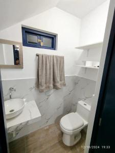 a white bathroom with a toilet and a sink at CASA DE PLAYA FRENTE AL MAR k173 in San Vicente de Cañete