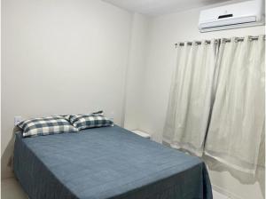 Un dormitorio con una cama con una manta azul y una ventana. en Lençóis Confort - Apartamento, en Barreirinhas 7 fotos más