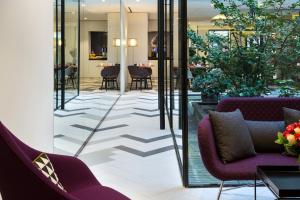 a lobby with purple chairs and tables and glass walls at Citadines Opéra Paris in Paris