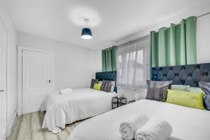 two beds in a room with green curtains at 3 Bedrooms Homely House in Motherwell Sleeps 8 comfortably with 6 double beds Near Glasgow Edinburgh Free Private Parking Business Travellers Contractors Holiday Goers Near all Major transport links in Carfin