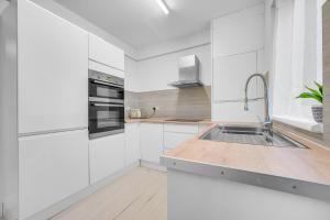 a kitchen with white cabinets and a stainless steel sink at 3 Bedrooms Homely House in Motherwell Sleeps 8 comfortably with 6 double beds Near Glasgow Edinburgh Free Private Parking Business Travellers Contractors Holiday Goers Near all Major transport links in Carfin
