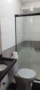 a bathroom with a toilet and a glass shower at Kitnet para Hospedagem in Caruaru