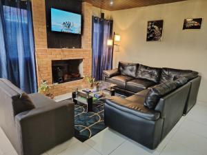 a living room with leather furniture and a fireplace at Cabaña Falda del Volcán Barú Planta alta in Paso Ancho
