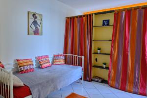 1 dormitorio con 1 cama con cortinas coloridas y estante en colibri, en Bouillante