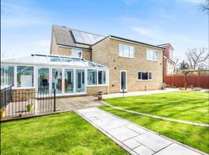 a house with a conservatory and a lawn at Vancouver Place in Orpington