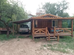 a small wooden cabin with a porch and a truck at La exclusiva in Cosquín