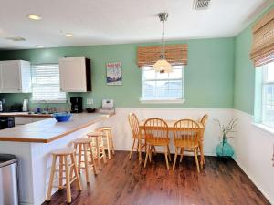 a kitchen with wooden chairs and a table with a counter at Casa de las Olas - Huge Fenced Yard, Massive Outdoor Shower, Great Breezes From Deck! in Surfside Beach