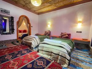a bedroom with two beds and a mirror at Auberge oued dades in Boumalne Dades