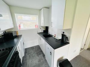 a kitchen with white cabinets and a black counter top at 2 Bedroom Chalet SB172, Sandown Bay, Isle of Wight, Free WiFi in Isle of Wight