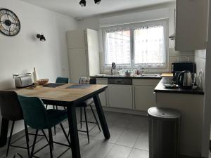 a kitchen with a wooden table and chairs and a counter at Appartement comme une Maison in Ingersheim