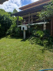 a house with a balcony and a grass yard at Pousada Minha Rosa Paixão - PRAIA DO ROSA, SC in Imbituba