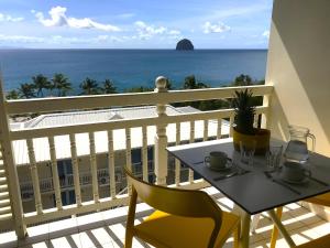 a balcony with a table and chairs and the ocean at Ti studio coquet vue mer 180 degrés face Diamant, piscine de standing in Le Diamant