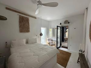 una camera da letto con un grande letto bianco e un ventilatore a soffitto di Boho Chic in Central Mpatsi! a Mpatsi (Batsi)