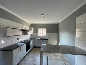 a kitchen with white cabinets and a large counter top at Waterfall Deluxe in Rustenburg +17 photos