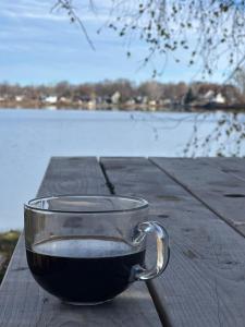 eine Tasse Kaffee auf einem Tisch in der Nähe eines Wasserkörpers in der Unterkunft 20 Minutes de Montréal, 1 chambre et 2 lits pour maximum 4 personnes in Pointe-Calumet