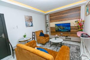 阿克拉Aster Luxury Apt close to Airport & Mall with Rooftop pool & gym的客厅里有一张沙发和两把椅子