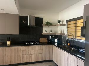 a kitchen with wooden cabinets and a black counter top at Casa Milos 7 Min from the Consulate in Manuel F. Martínez
