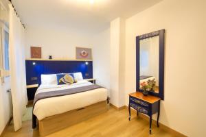una camera da letto con un letto con testiera blu e uno specchio di Oviedo Centro Apartastur26, en calle Gascona a Oviedo