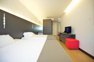 a hotel room with two beds and a tv at Mercure Nerocubo Rovereto in Rovereto