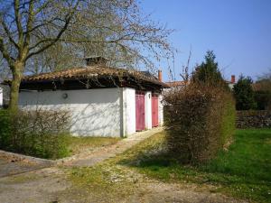 a white building with a red door next to a yard at Aire Du Verger in Palluau