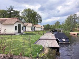 a boat docked next to a house on a river at Lakeside Farm Stay, Friesland in Sint Nicolaasga