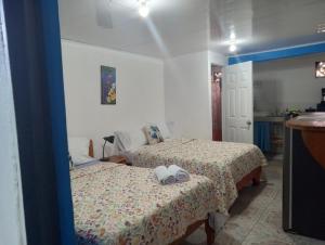 a bedroom with two beds and a kitchen at Cabina Chazu#1 in Quepos