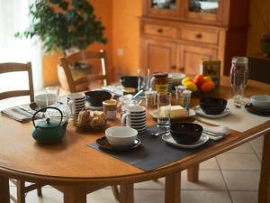 a wooden table with plates and bowls of food on it at Chambre cosy avec terrasse et jardin proche Puy-en-Velay - FR-1-582-526 in Saint-Germain-Laprade