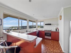 cocina con armarios rojos y ventana grande en Grandview Holiday Beach House, en Gracetown
