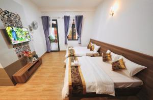 two beds in a hotel room with a tv at Thanh Hang Hotel Dalat in Khu Chi Lăng