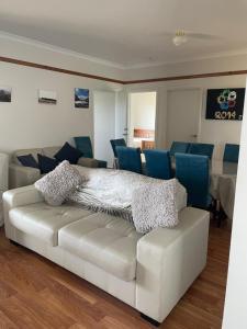 a living room with a white couch and blue chairs at Inspiration House in Clayton Bay