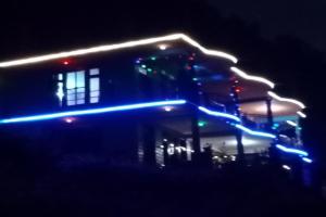 a building with lights on it at night at Hotel O Snow Pine Guest House Tosh in Manīkaran