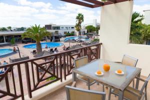 a balcony with tables and chairs and a pool at Vitalclass Lanzarote Resort in Costa Teguise