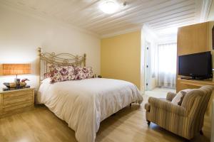 a bedroom with a bed and a tv and a chair at Casa Gialla Campos do Jordão in Campos do Jordão +22 photos