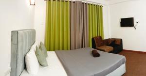 a bedroom with a bed with a green curtain and a chair at The Blues Chalet in Nuwara Eliya