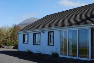 a white house with glass windows and a mountain at Kilsallagh Cottage in Westport