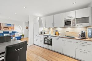 ノルトダイヒにあるAm-Nordmeerstrandの白いキャビネットとカウンタートップを備えたキッチン