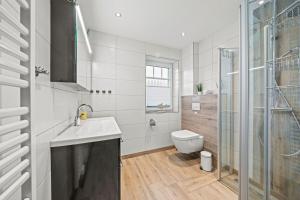 ノルトダイヒにあるAm-Nordmeerstrandのトイレ、洗面台、シャワー付きのバスルーム +14枚の写真