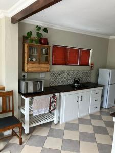 a kitchen with white cabinets and a black counter top at Carneddie cottage-garden in Bredasdorp